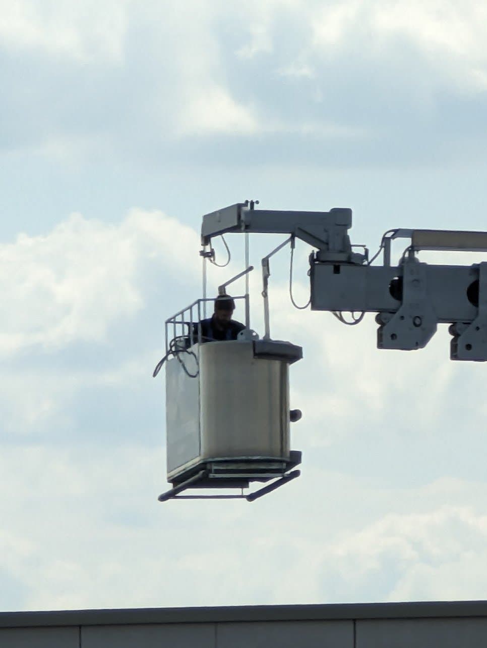 Technician working from the building's own BMU cradle, out over the roof edge