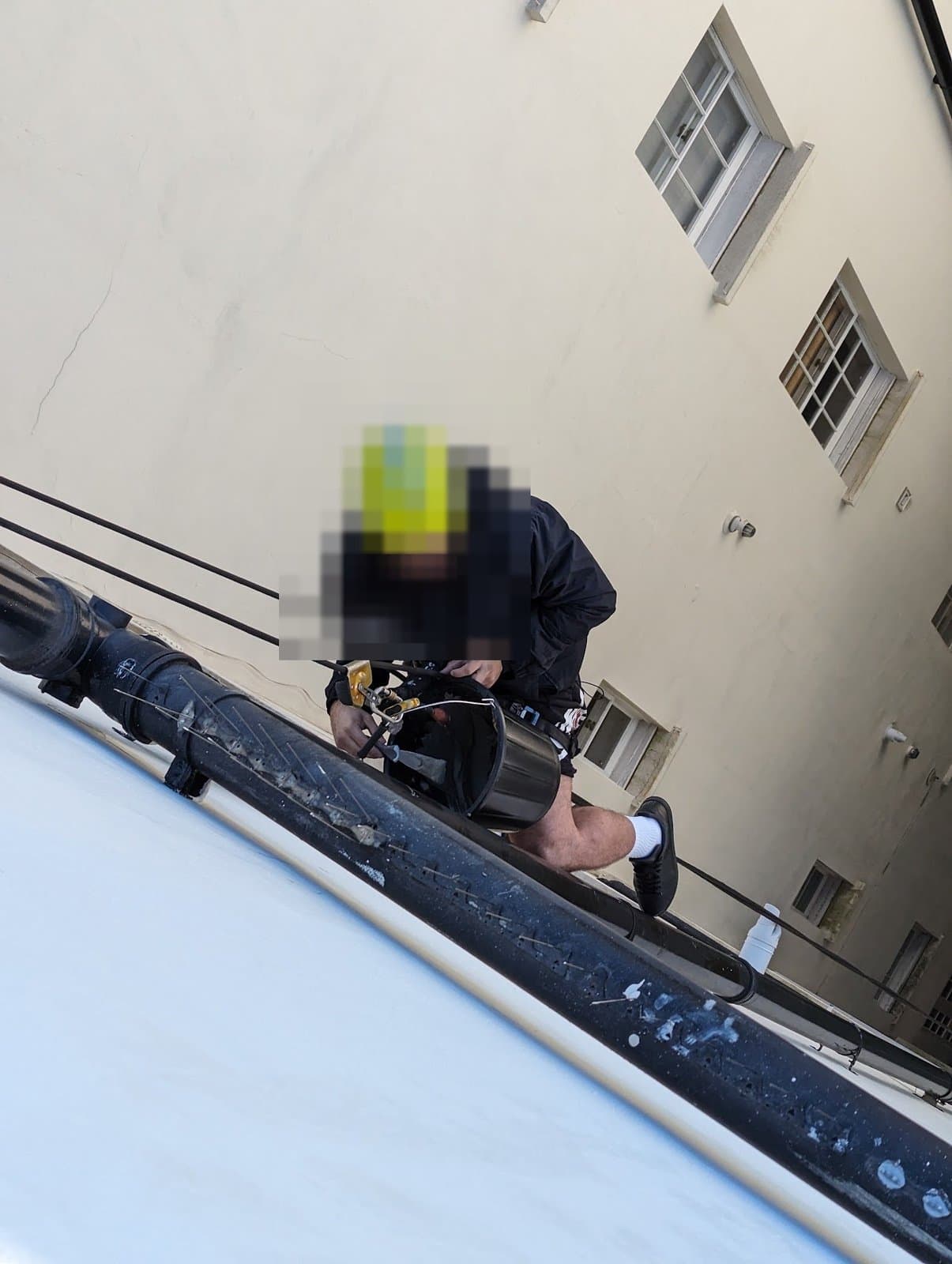 IRATA technician suspended in the lightwell with a mortar bucket on the harness, alongside the cast-iron downpipe