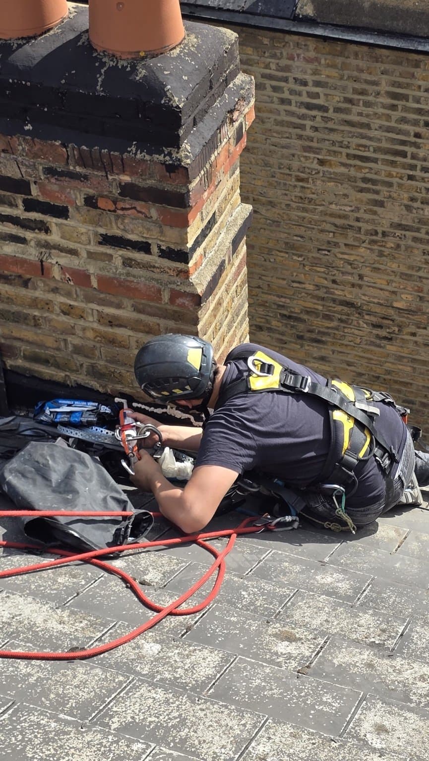 Technician working at the lead soaker line where the chimney meets the slate roof