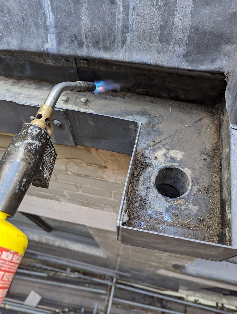 Torch-welding the lead seam beside a gutter outlet