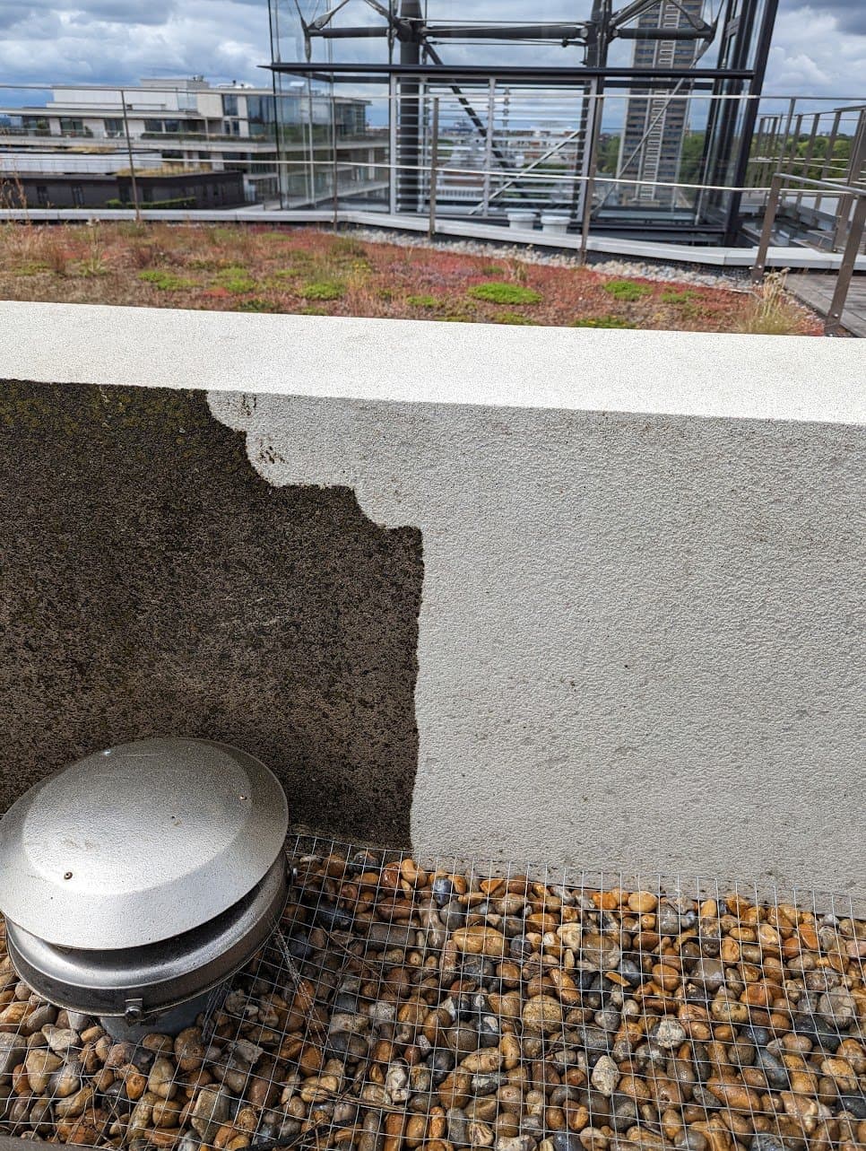 Rooftop parapet mid-clean, half still black with dirt and half washed back to white