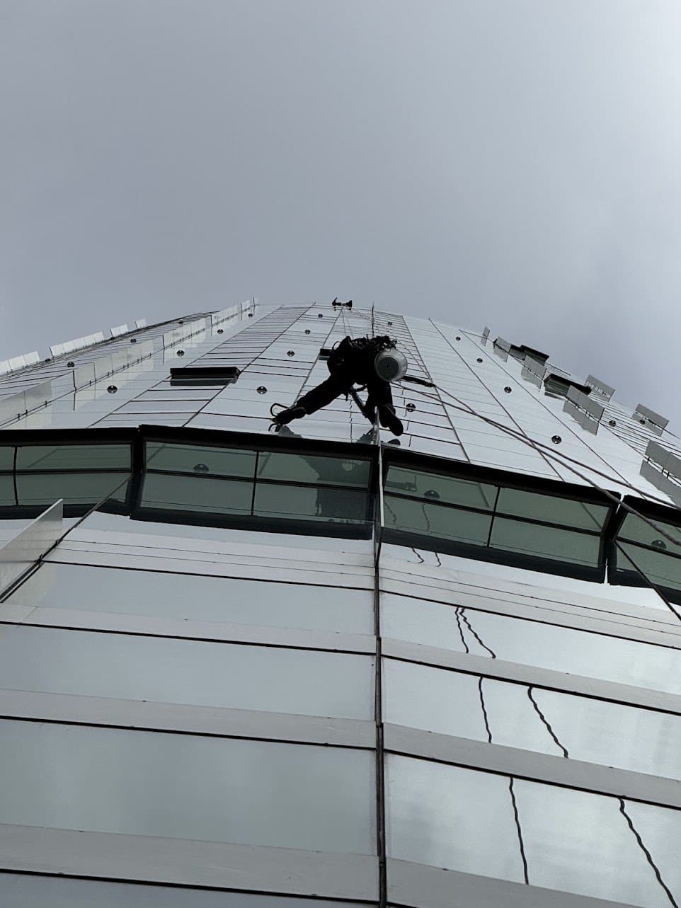 Technician silhouetted against a curved reflective glass tower