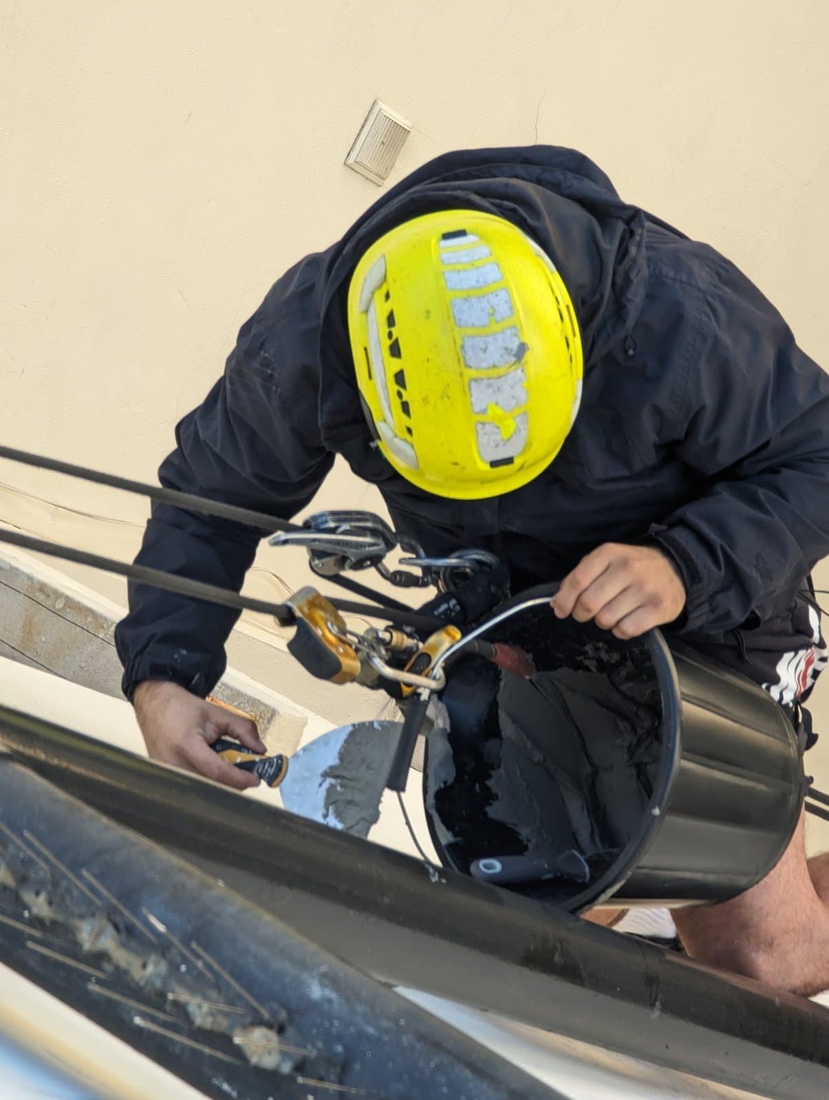 Loading the trowel from the bucket, filling the render cracks by hand at the defect