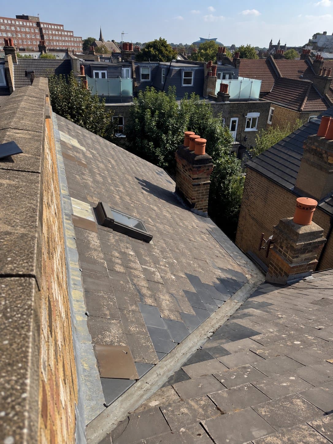 The roof slope with new slates set into the existing courses beside the lead valley