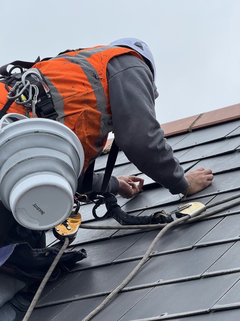 Close view of the technician working between courses of flat interlocking tiles