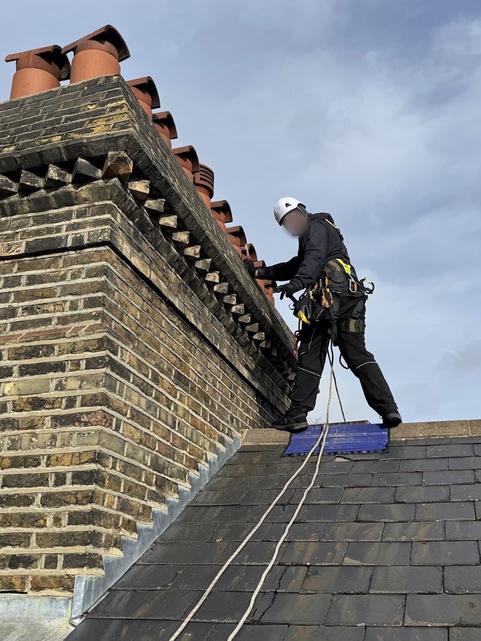Technician beside a tall Victorian chimney stack with eight clay pots